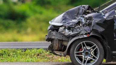 A black car with front-end damage after a car accident.