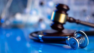A judge’s gavel and a stethoscope lying on a glass table, representing a medical malpractice lawsuit.
