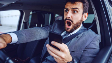 Man in a suit texting while driving, which is one of the main causes of multi-car accidents.
