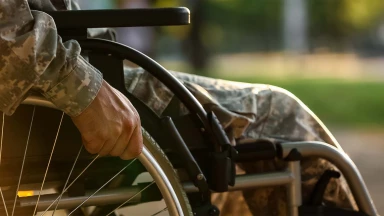 A man wearing an army uniform sits in a wheelchair as a result of spinal injuries.