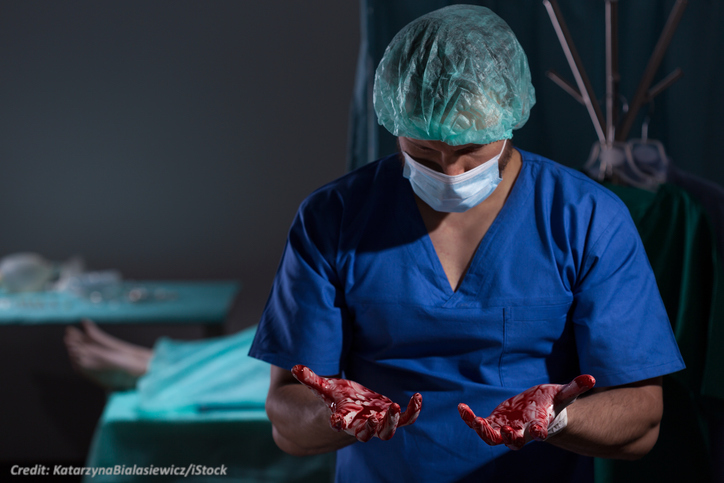 Image of a surgeon with blood on his hands